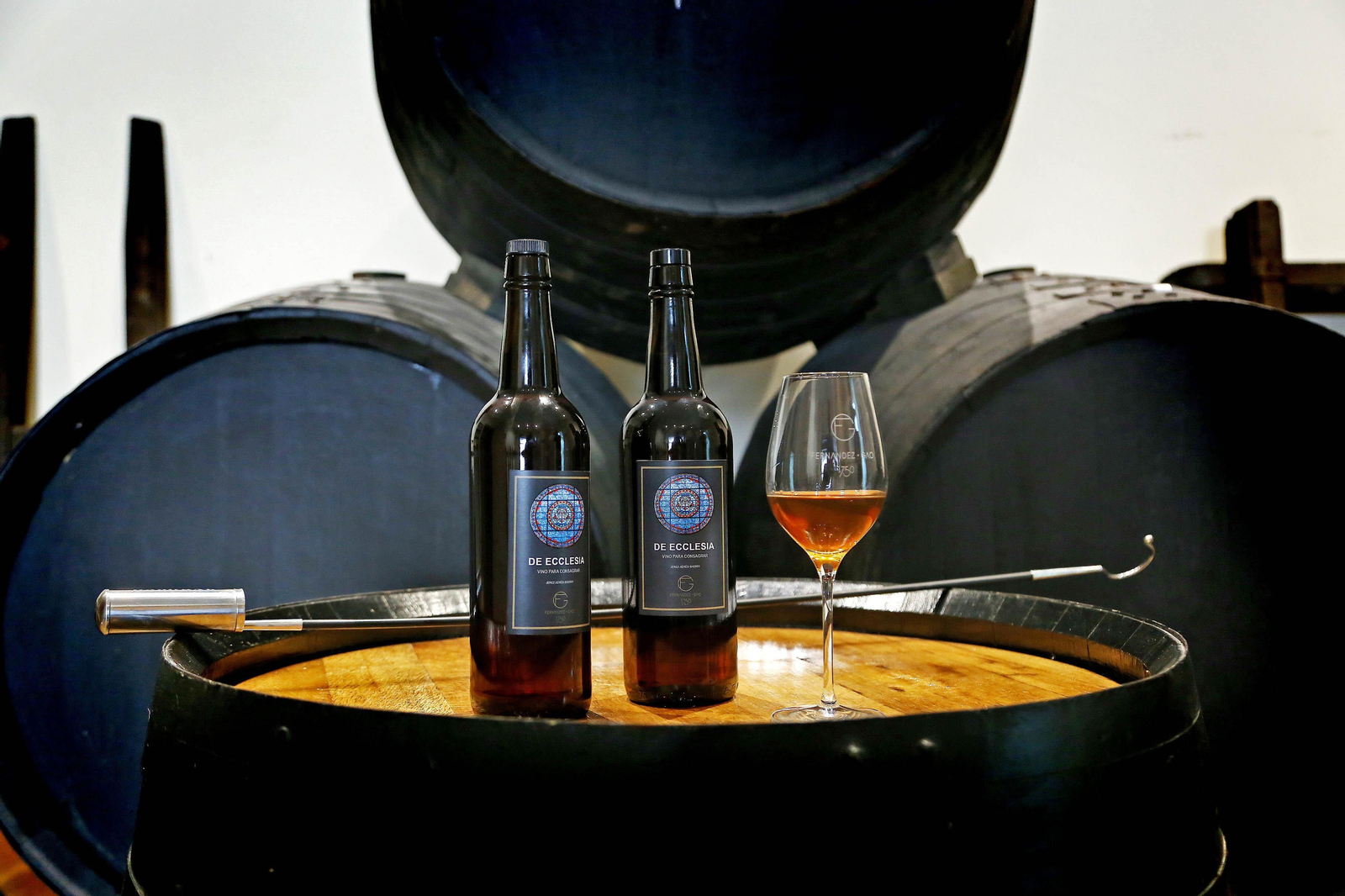 1. Dos botellas de la marca 'De Ecclesia',, la nueva gama de vinos de misa de la bodega jerezana Fernández-Gao junto a una copa de vino con el caldo servido. 2. Juan Carlos Sánchez Gago le muestra a Juan Antonio Vital la botella de su nueva gama de vinos de misa en la oficina del conjunto bodeguero 3. Una de las cabezas de toro que adorna la oficina de Fernández-Gao. 4. El director técnico de la bodega y el párroco de Algar posan con el vino de misa 'De Ecclesia'.