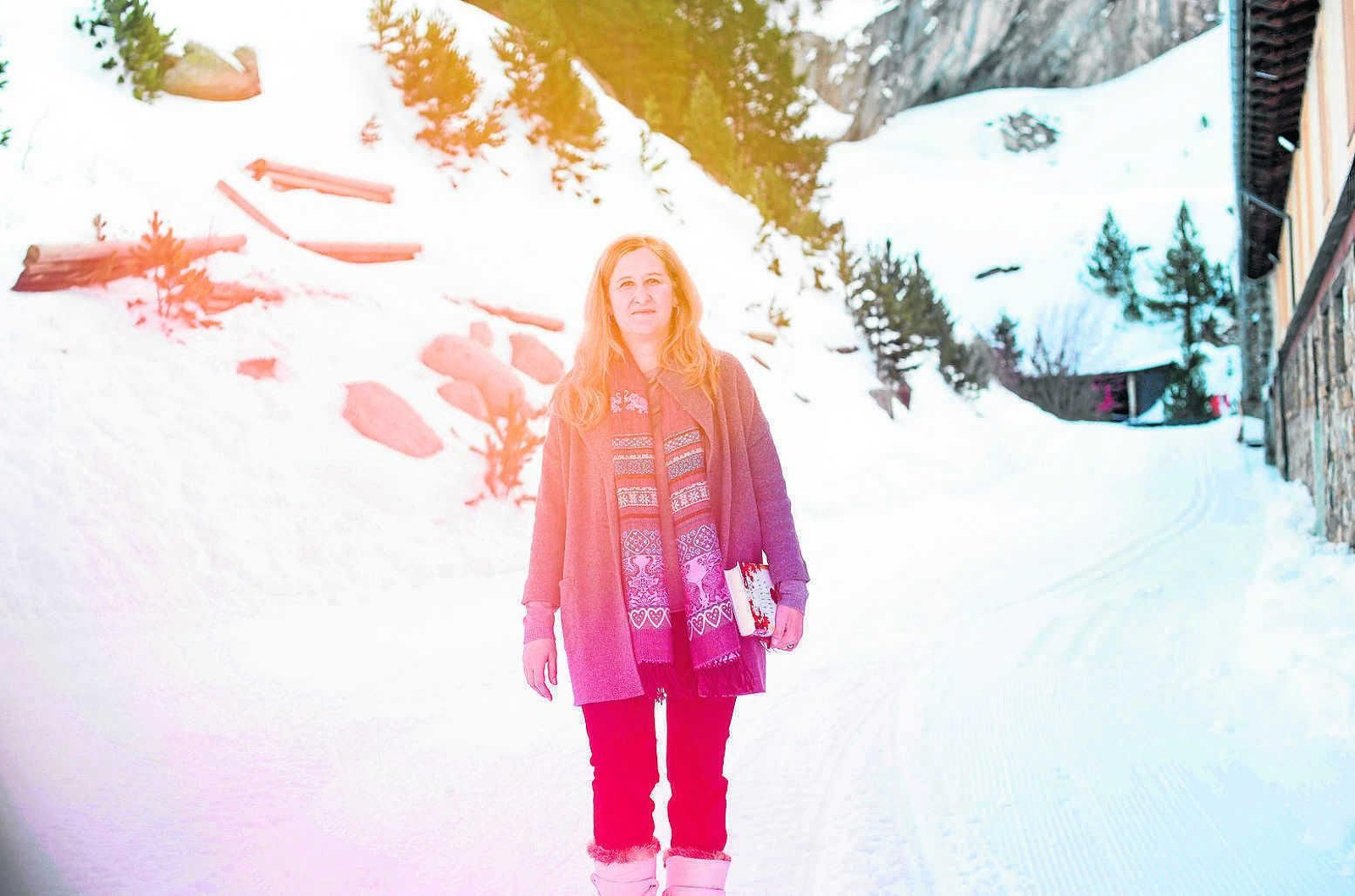 La escritora Luz Gabás, en la población aragonesa de Benasque, en el corazón de los Pirineos; abajo, un ejemplar de su nueva novela.