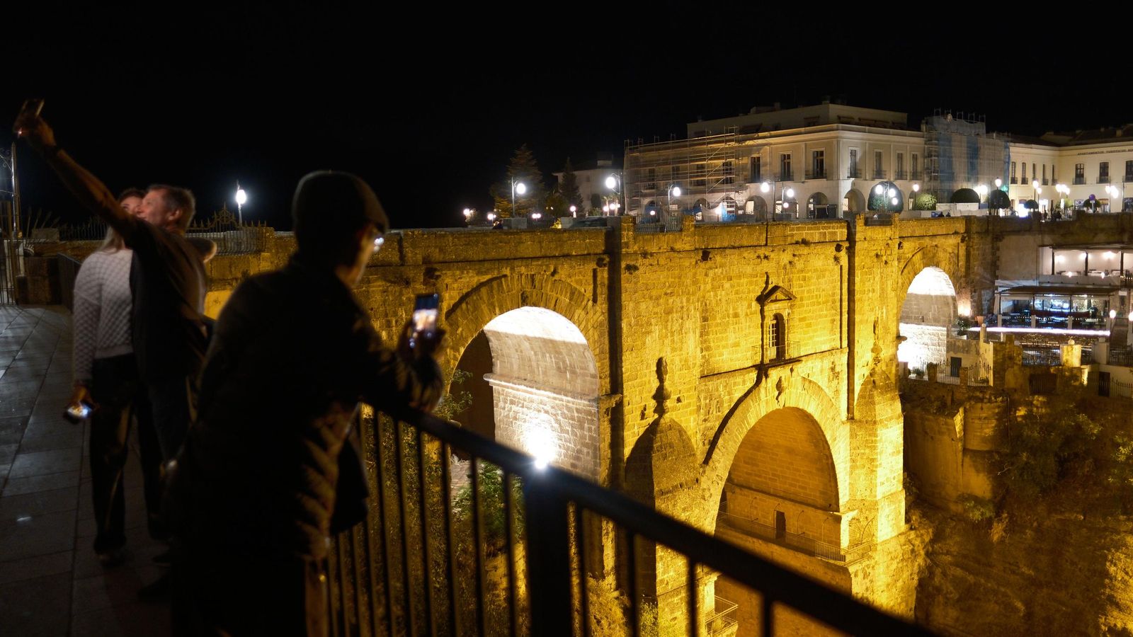 Turistas tomándose imágenes en el Puente Nuevo durante la noche.