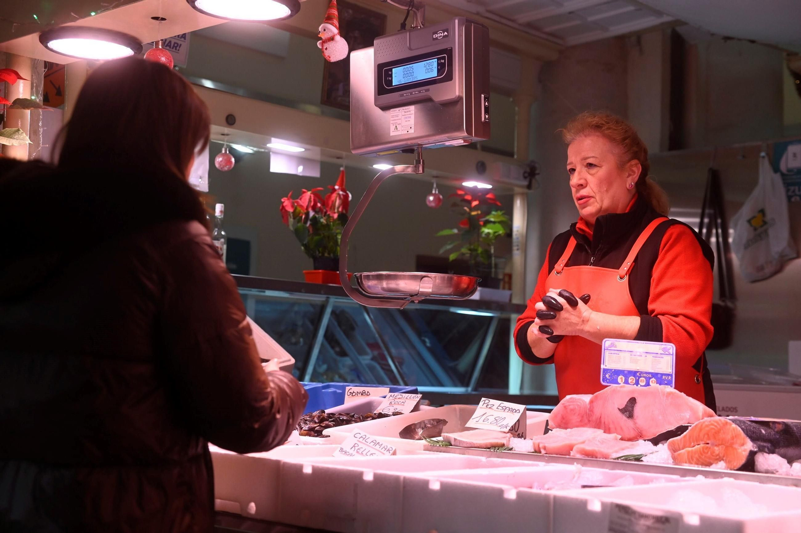 Una pescadera atiende a una cliente en el mercado de La Corredera.