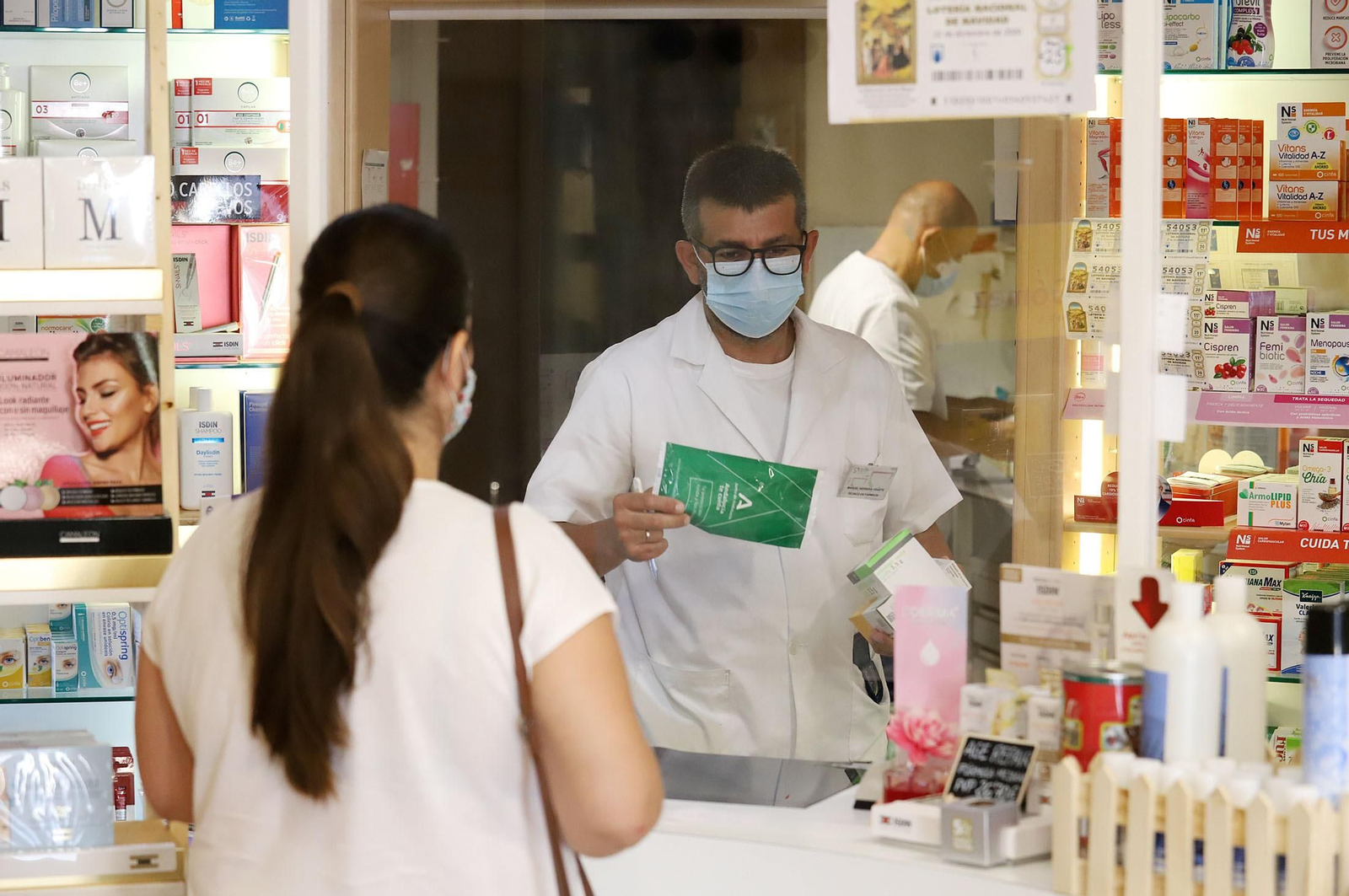 Una usuaria adquiere mascarillas en una farmacia de Huelva.