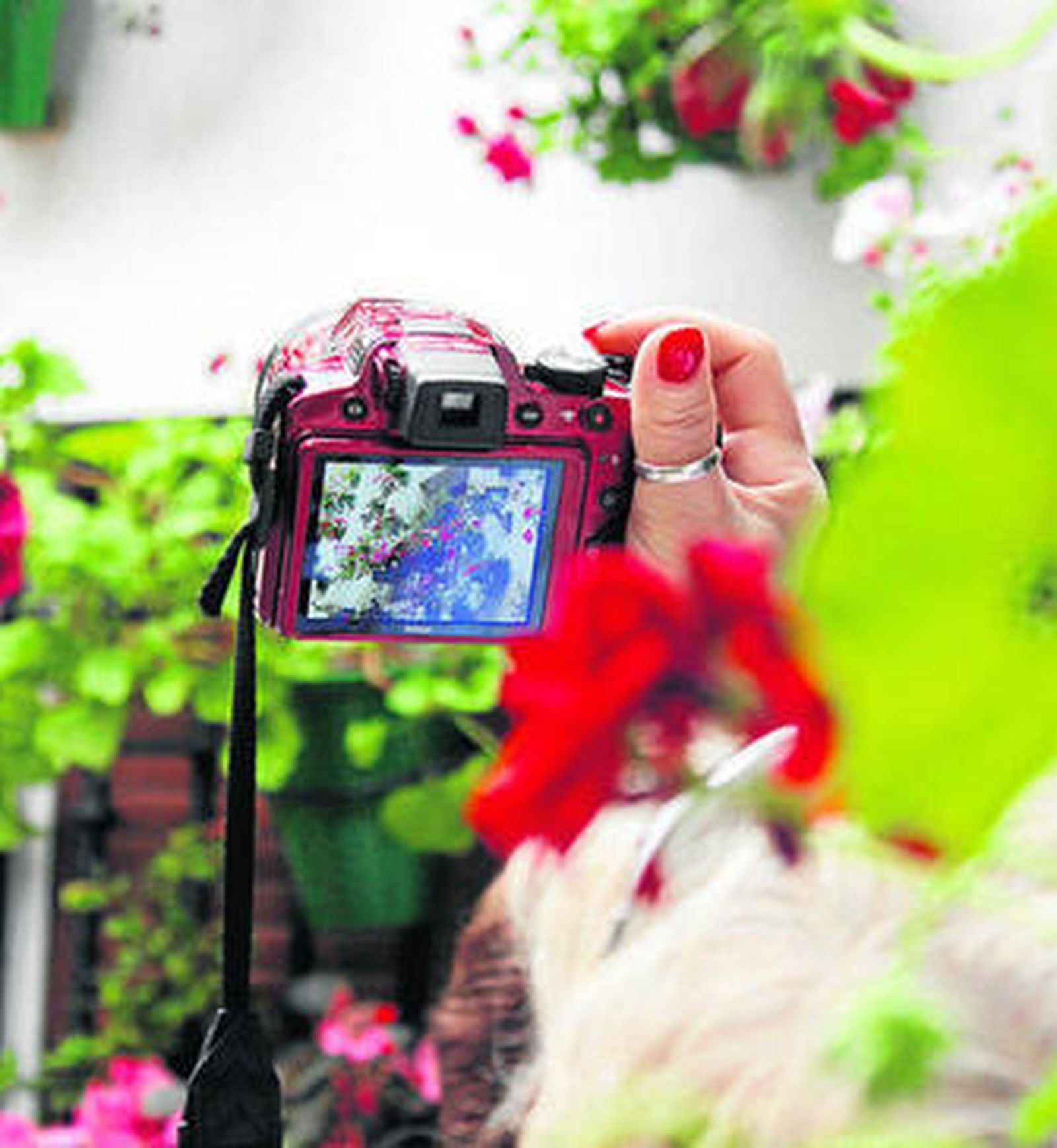 Una mujer realiza una fotografía en un patio cordobés.