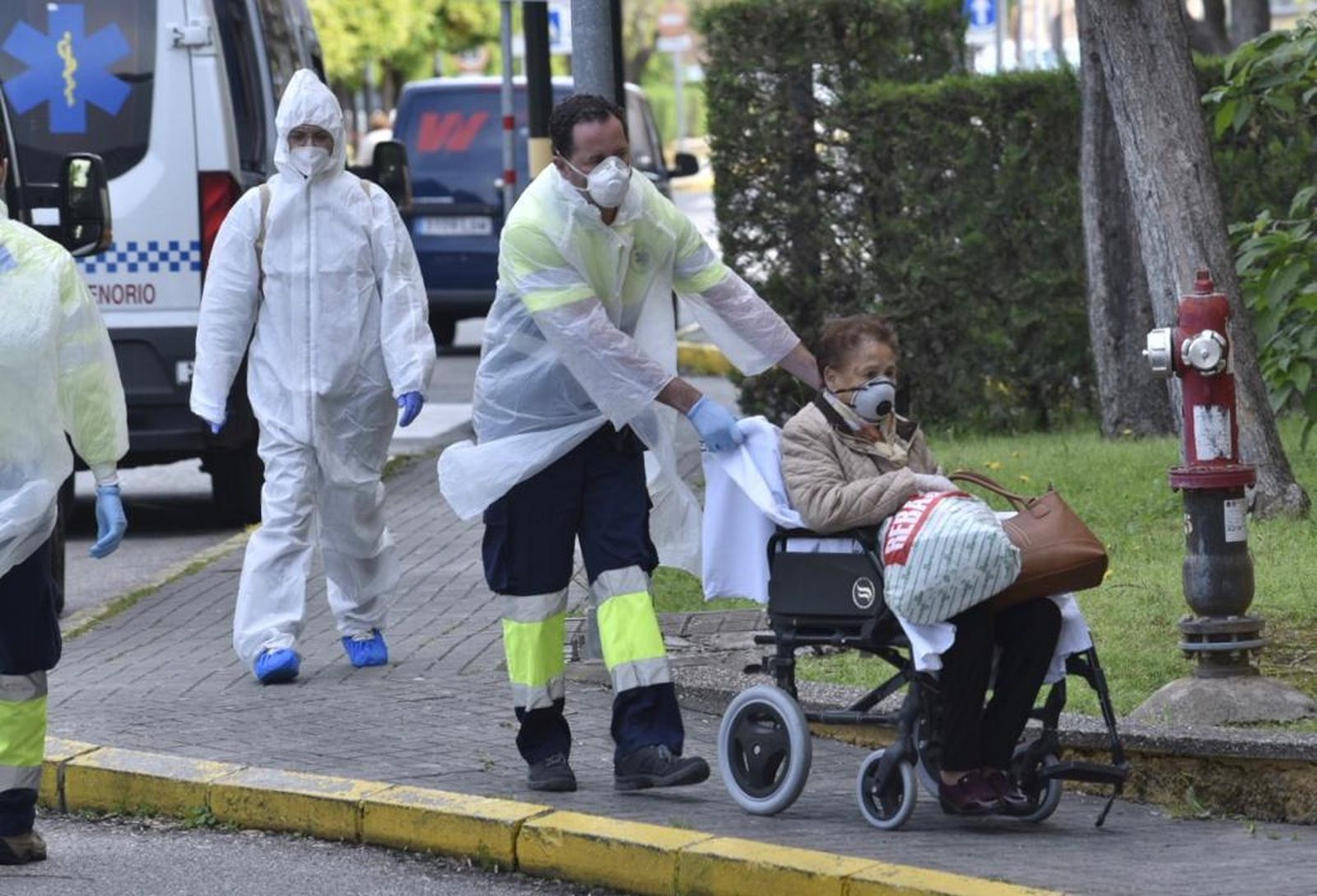 Una señora es trasladada al hospital Virgen Macarena por un sanitario.