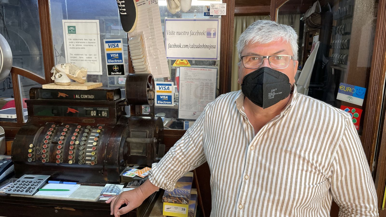 Alberto Hinojosa posa junto a una caja registradora del siglo XIX en su tienda de alpargatas.