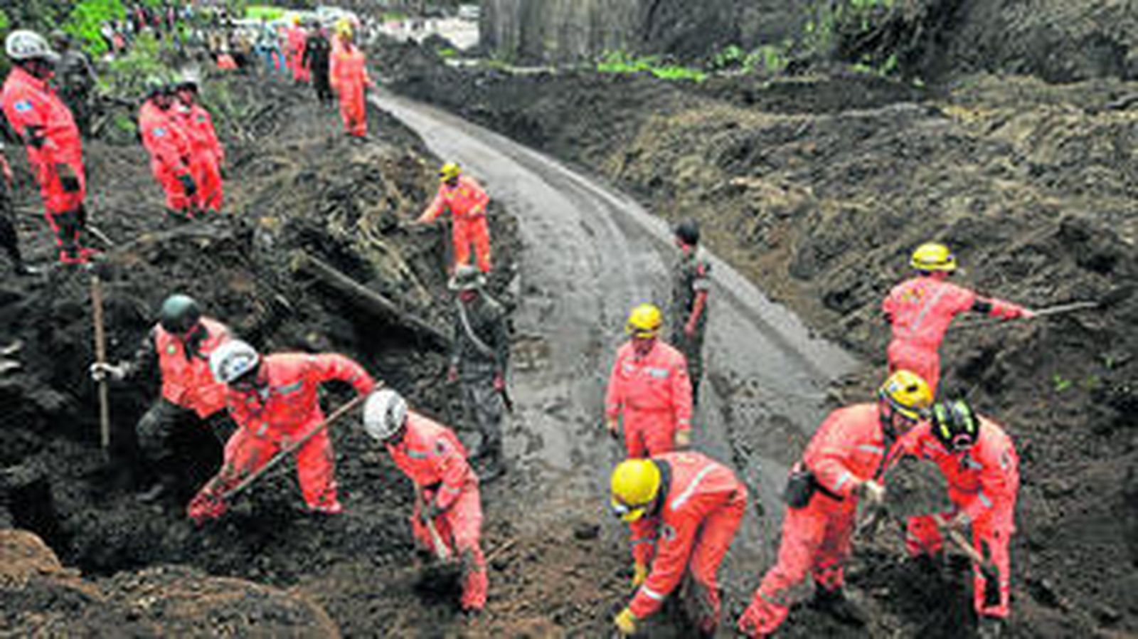 Operarios sacaban el barro en busca de víctimas tras un alud provocado por las fuertes lluvias, el domingo al oeste de Guatemala.