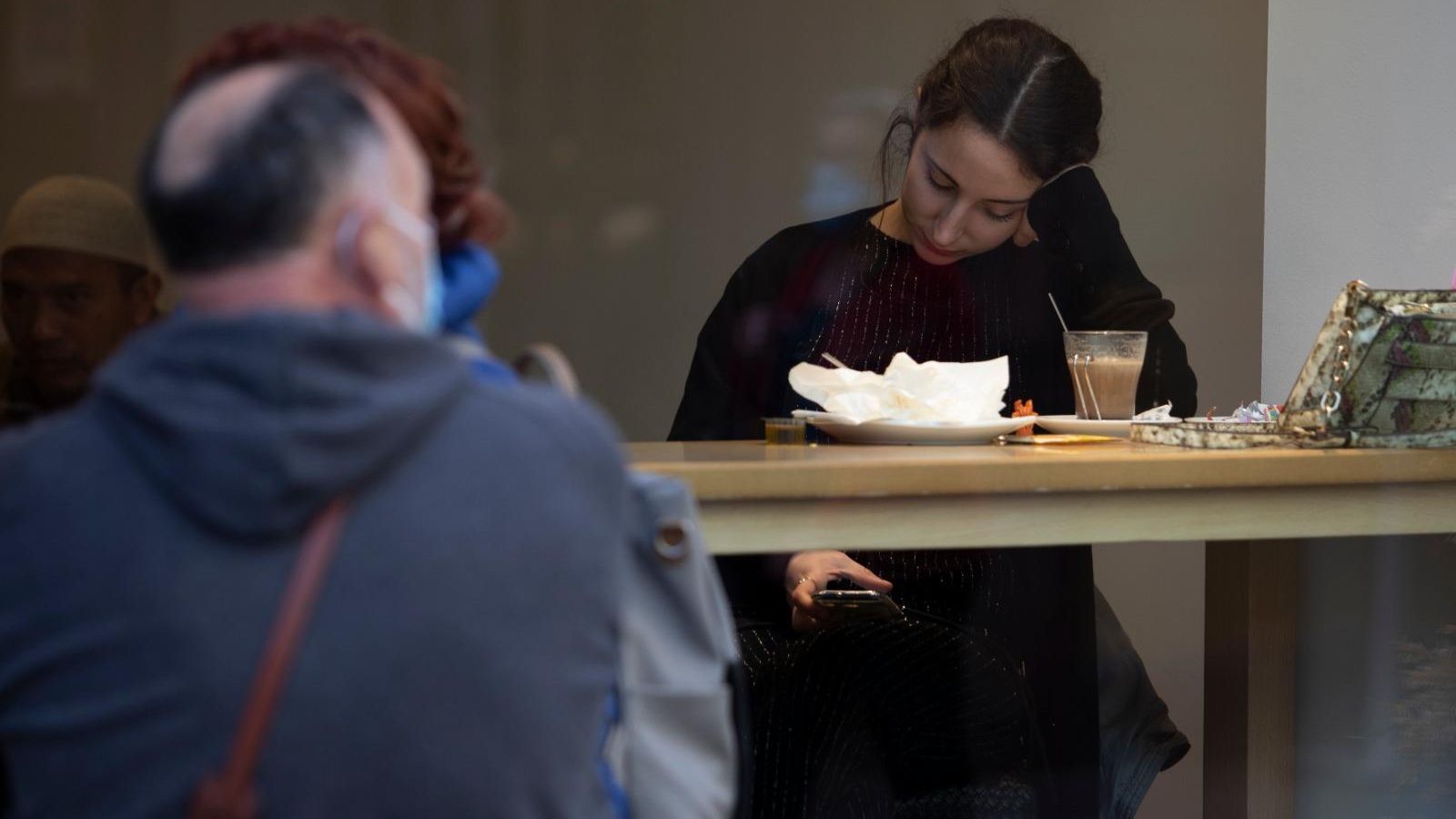 Una clienta de una cafetería del centro de Granada consulta su teléfono esta mañana