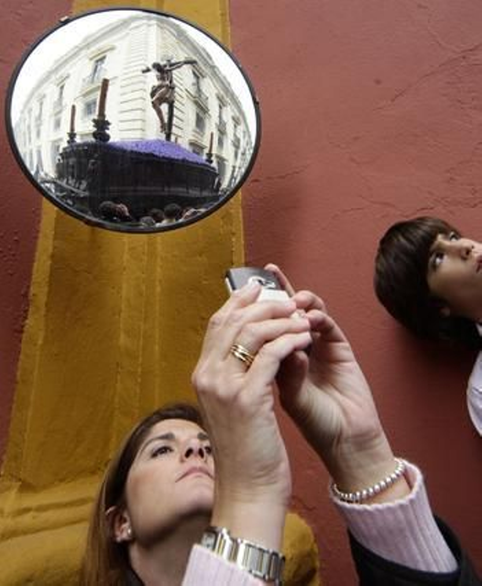 Una señora fotografía al Cristo de la Buena Muerte mientras éste se refleja en un espejo tras ella.

Foto: Antonio Pizarro