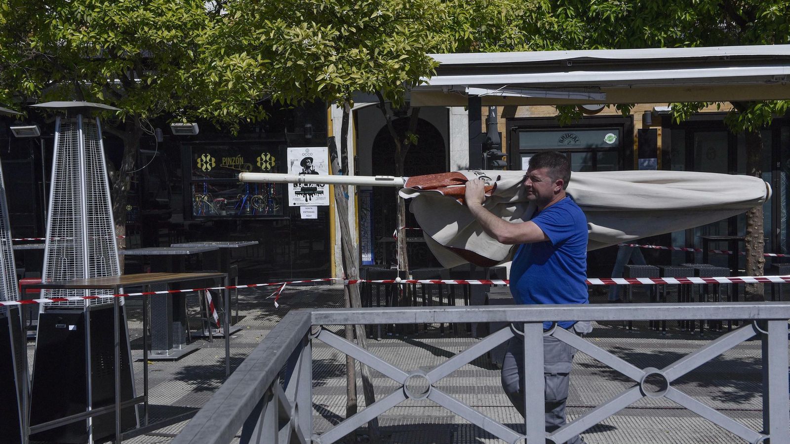 Un operario retira una sombrilla en uno de los bares del Paseo Colón.