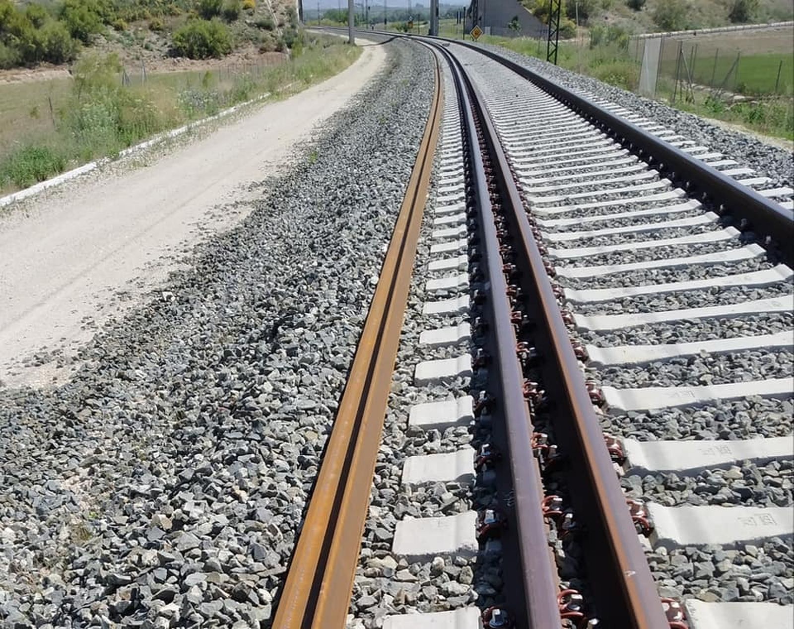 Tramos de carril recostados junto a la vía de ancho mixto de la línea AVE Granada-Antequera en mayo de 2019