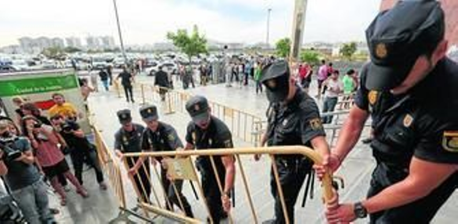 Agentes del Cuerpo Nacional de Policía colocan una valla para sustituir otra que se había roto al separar a los medios de comunicación de los acusados.