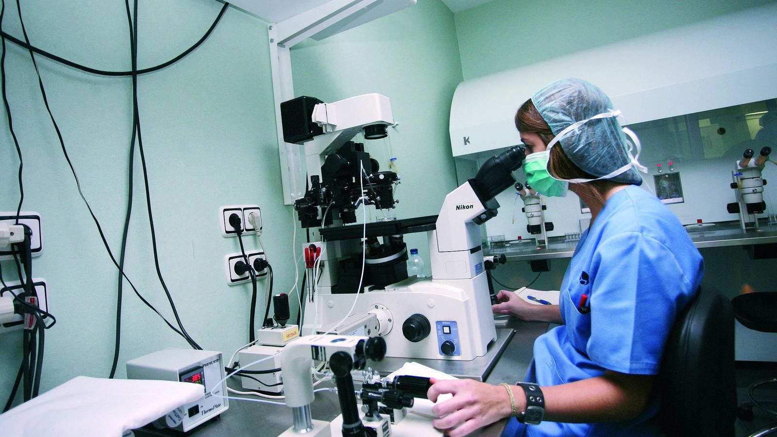 Una mujer trabaja con un microscopio en un laboratorio.