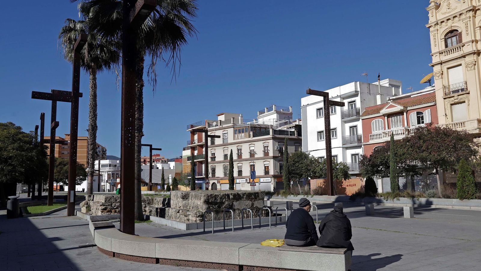 Dos personas descansan en los bancos del río de la Miel.