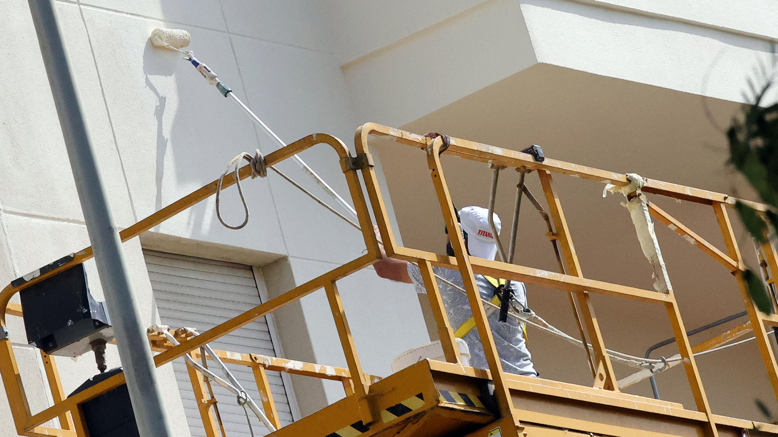 Un trabajador pintando una fachada de un edificio