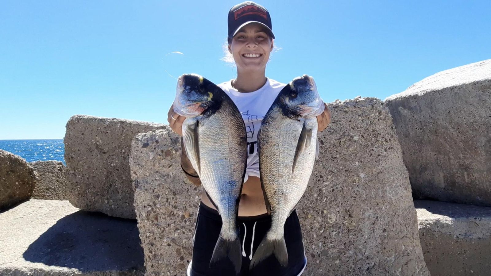 Bárbara muestra dos grandes doradas capturadas en el espigón de Huelva
