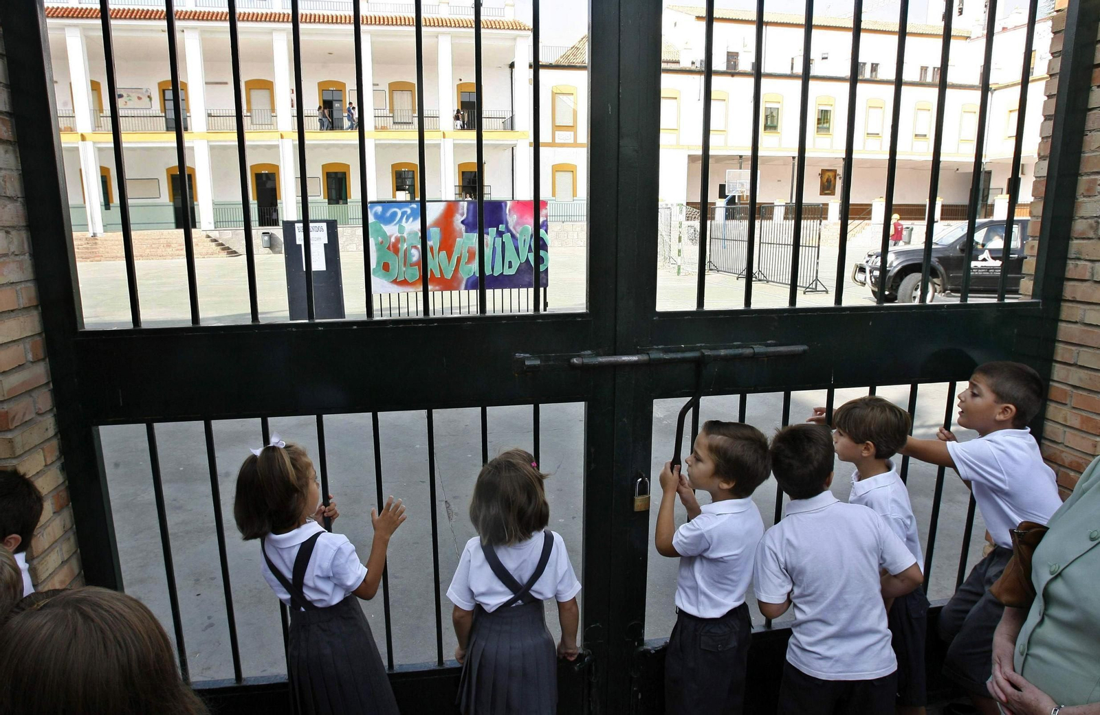 Escolares de la escuela concertada esperan en la puerta de un centro en Córdoba.