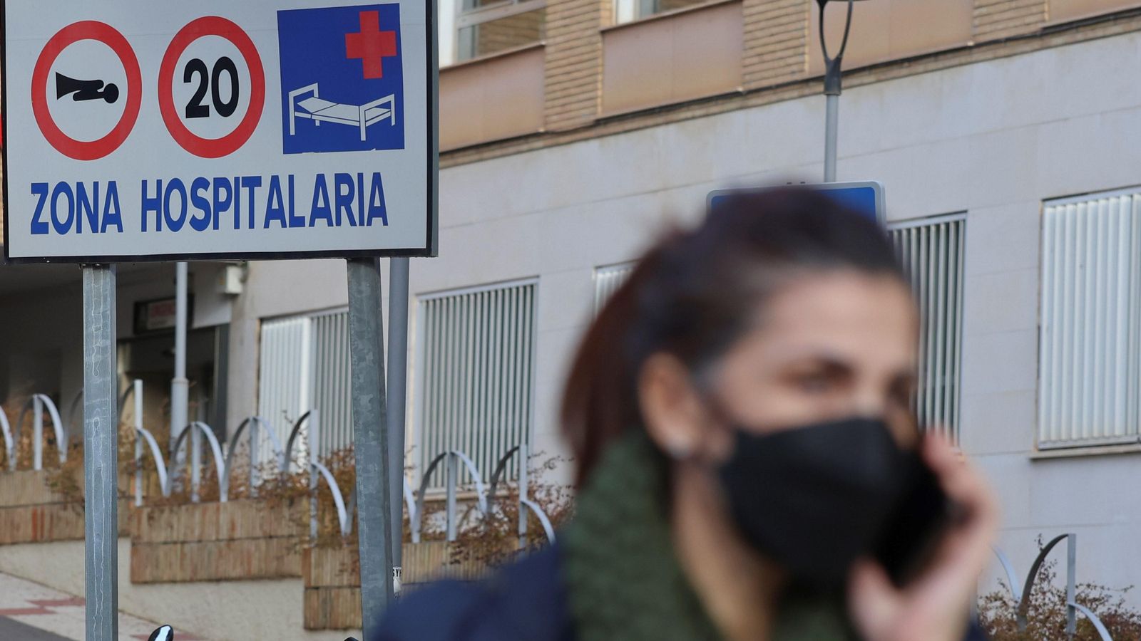 Una mujer con mascarilla pasa delante de un cartel del Hospital Regional.