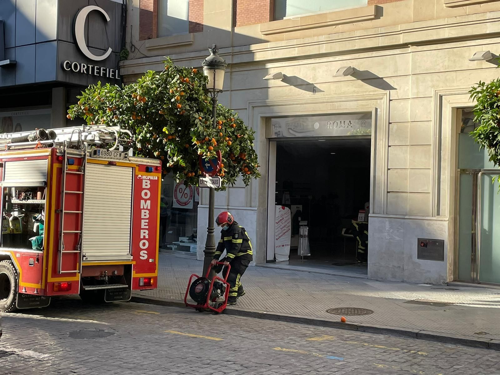 Los bomberos actúan en un incendio en la tienda Punto Roma del centro de Huelva.