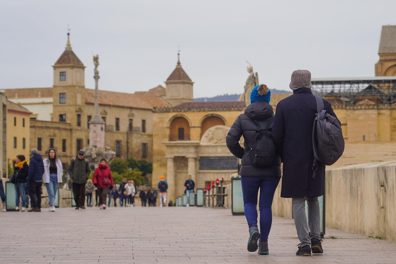 Transeúntes y turistas caminan por el Puente Romano de Córdoba.