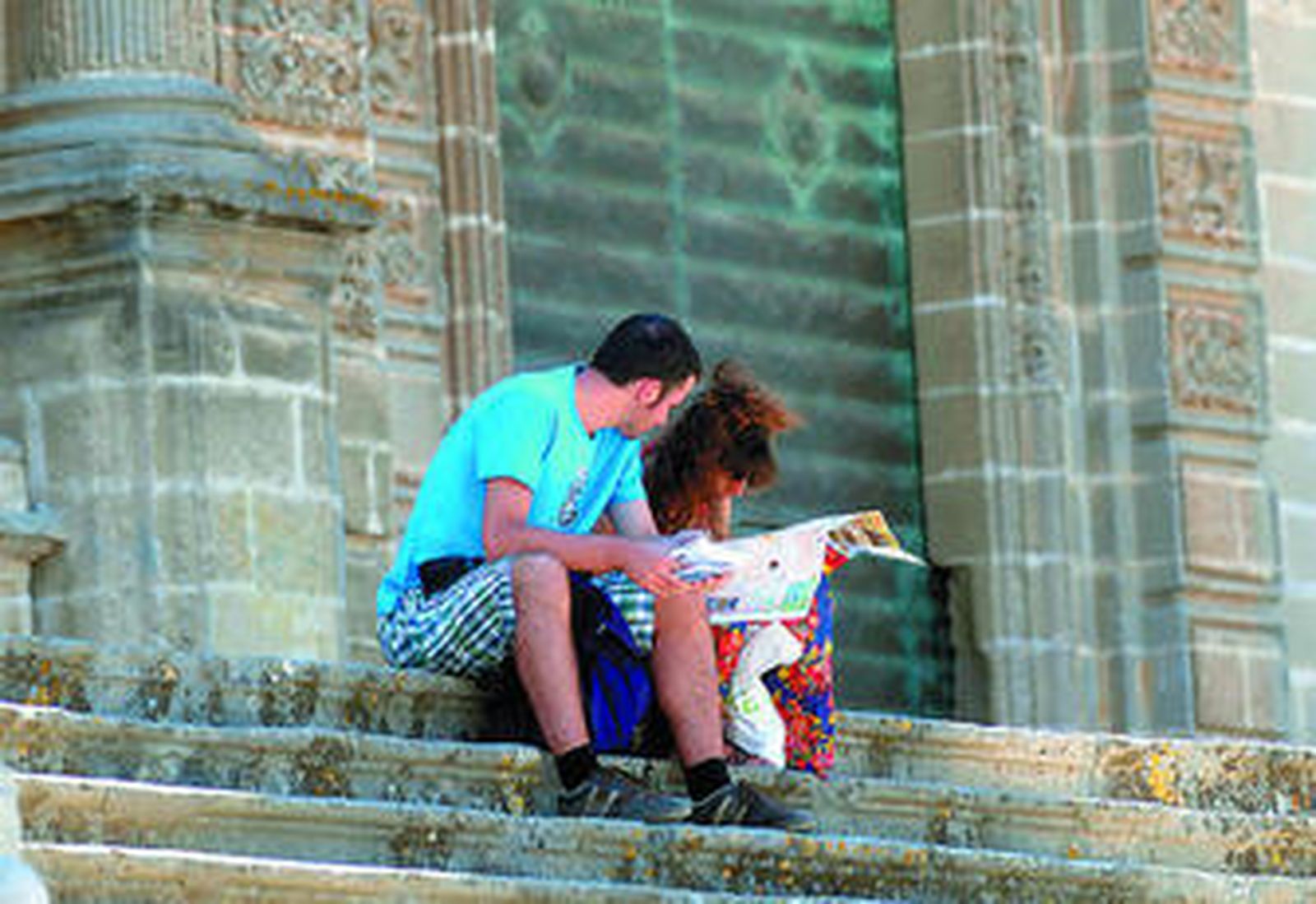 Una pareja de turistas consulta un callejero de Jerez sentada en la escalinata de la Catedral de Jerez.