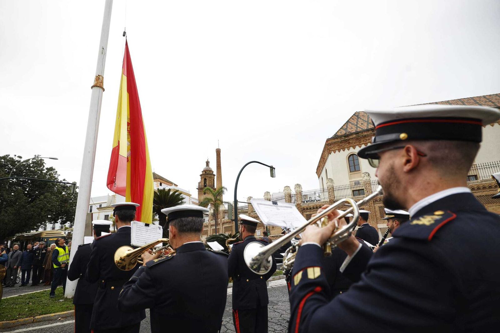 La banda del Tercio de la Armada interpreta el himno de España mientras se iza la bandera en la plaza de Sevilla.