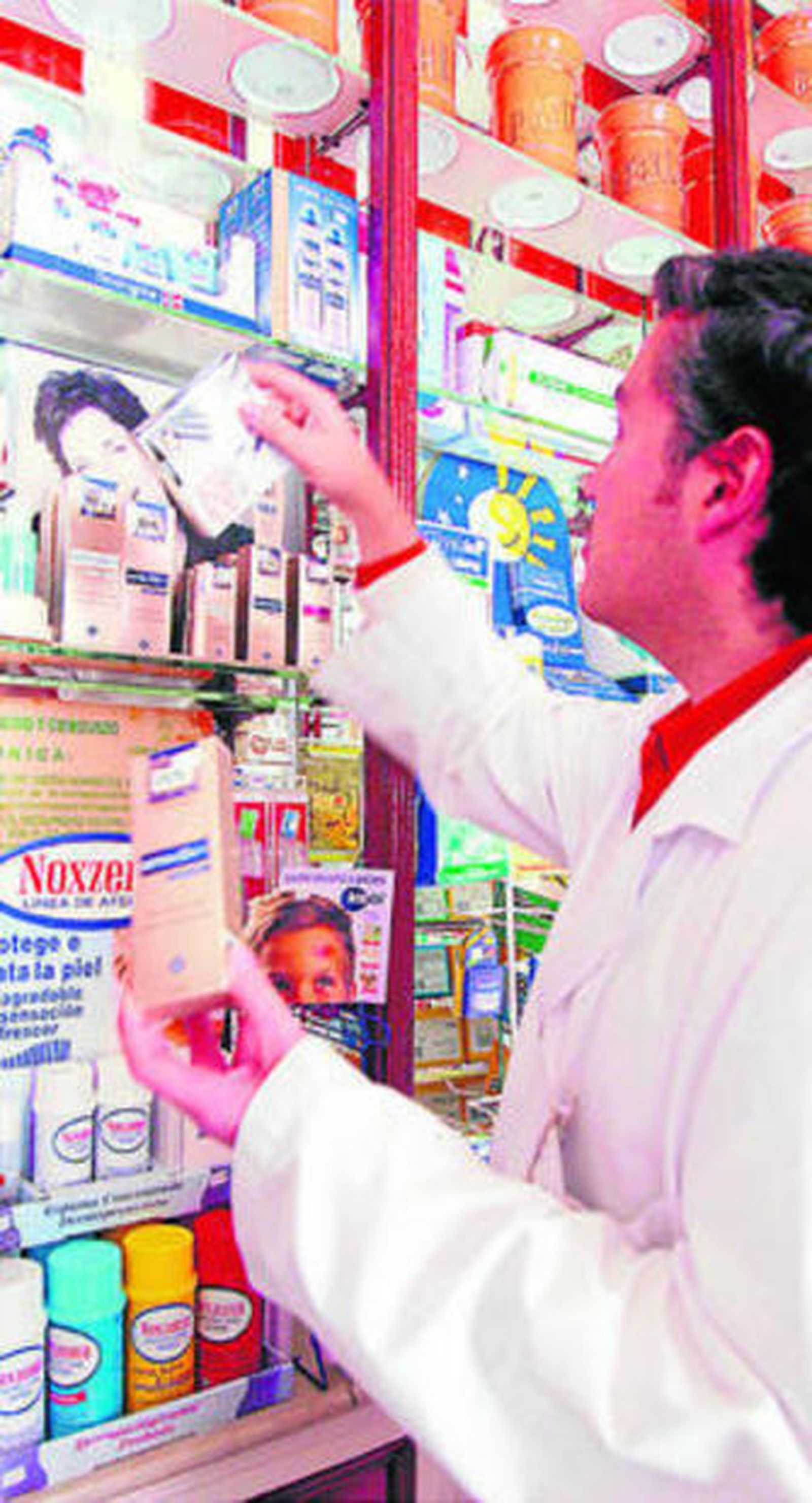 Un farmacéutico coloca medicamentos en una estantería.