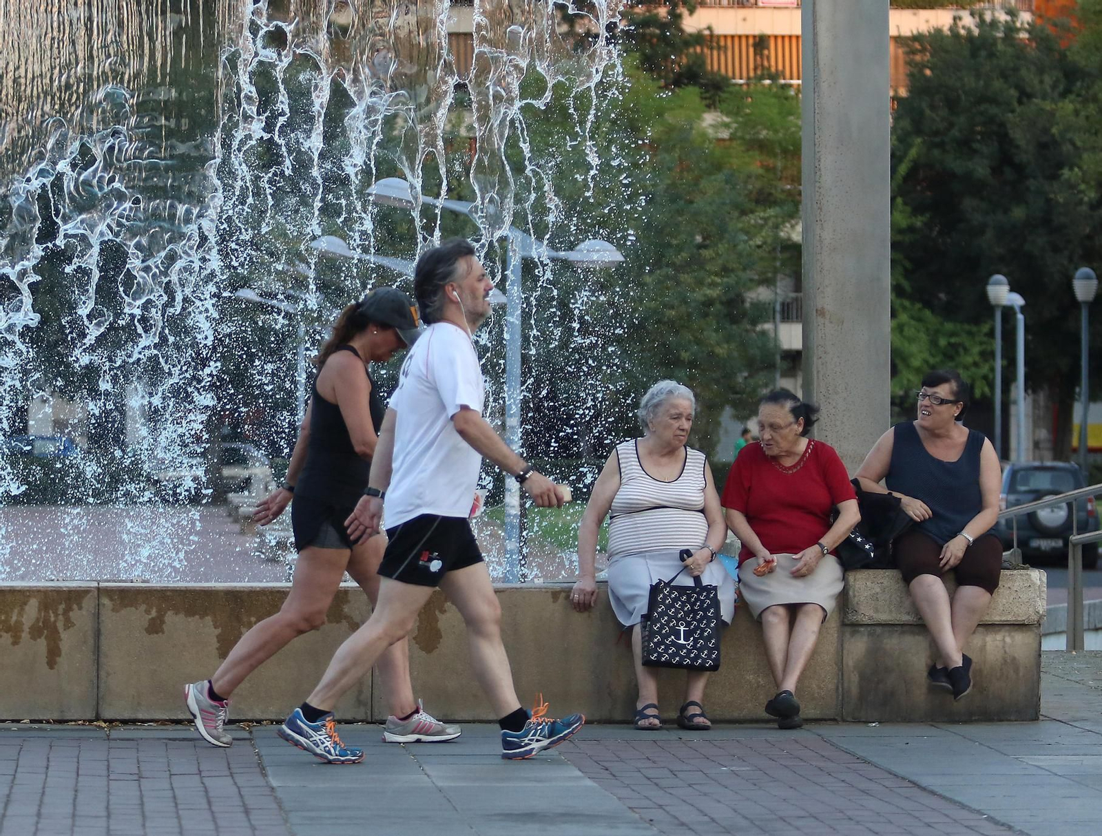 Una pareja practicando deporte pasa junto a una fuente del paseo de Córdoba.