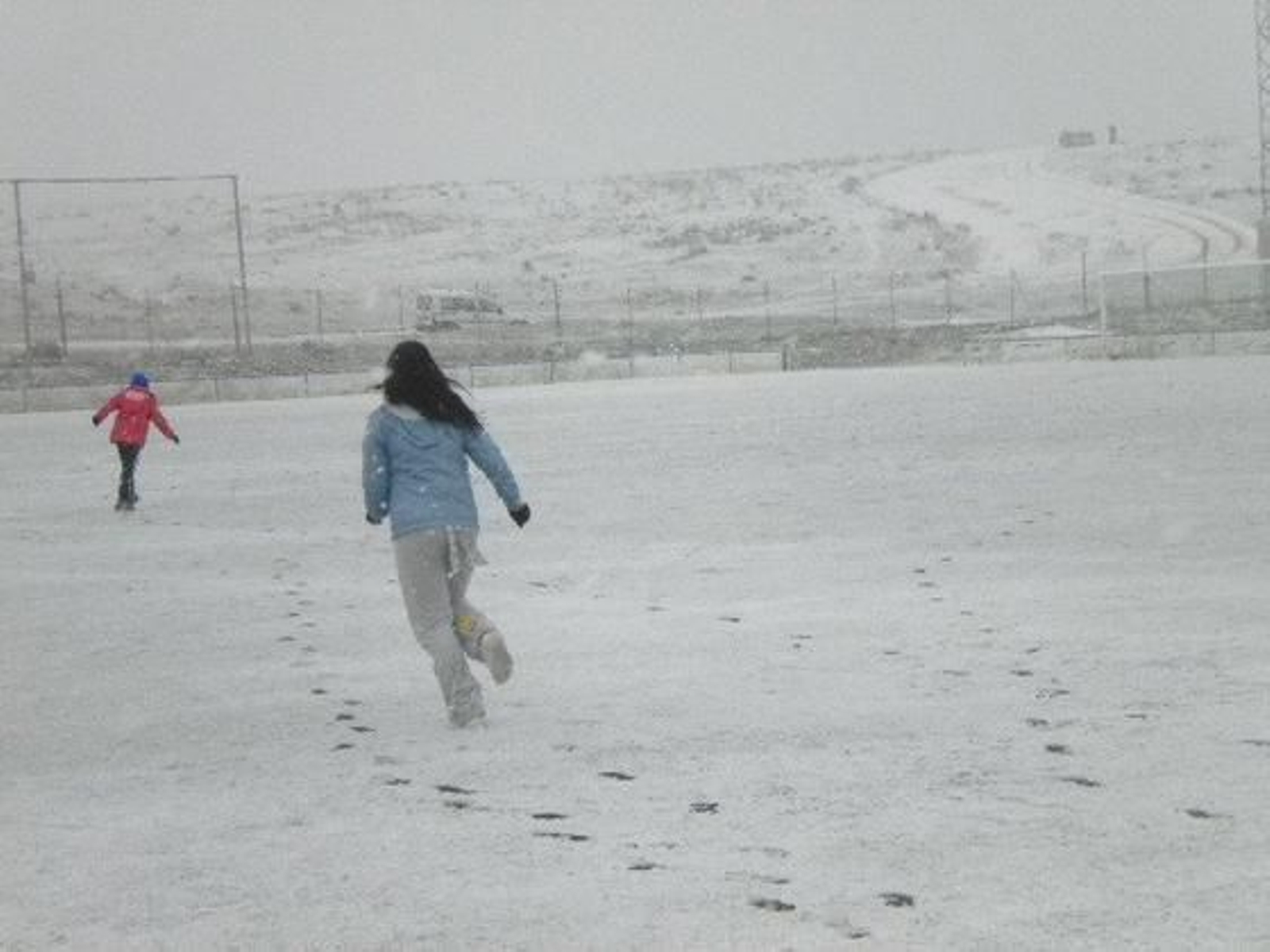 Dos niñas corren por un campo de fútbol completamente nevado./ María San Román Muñoz