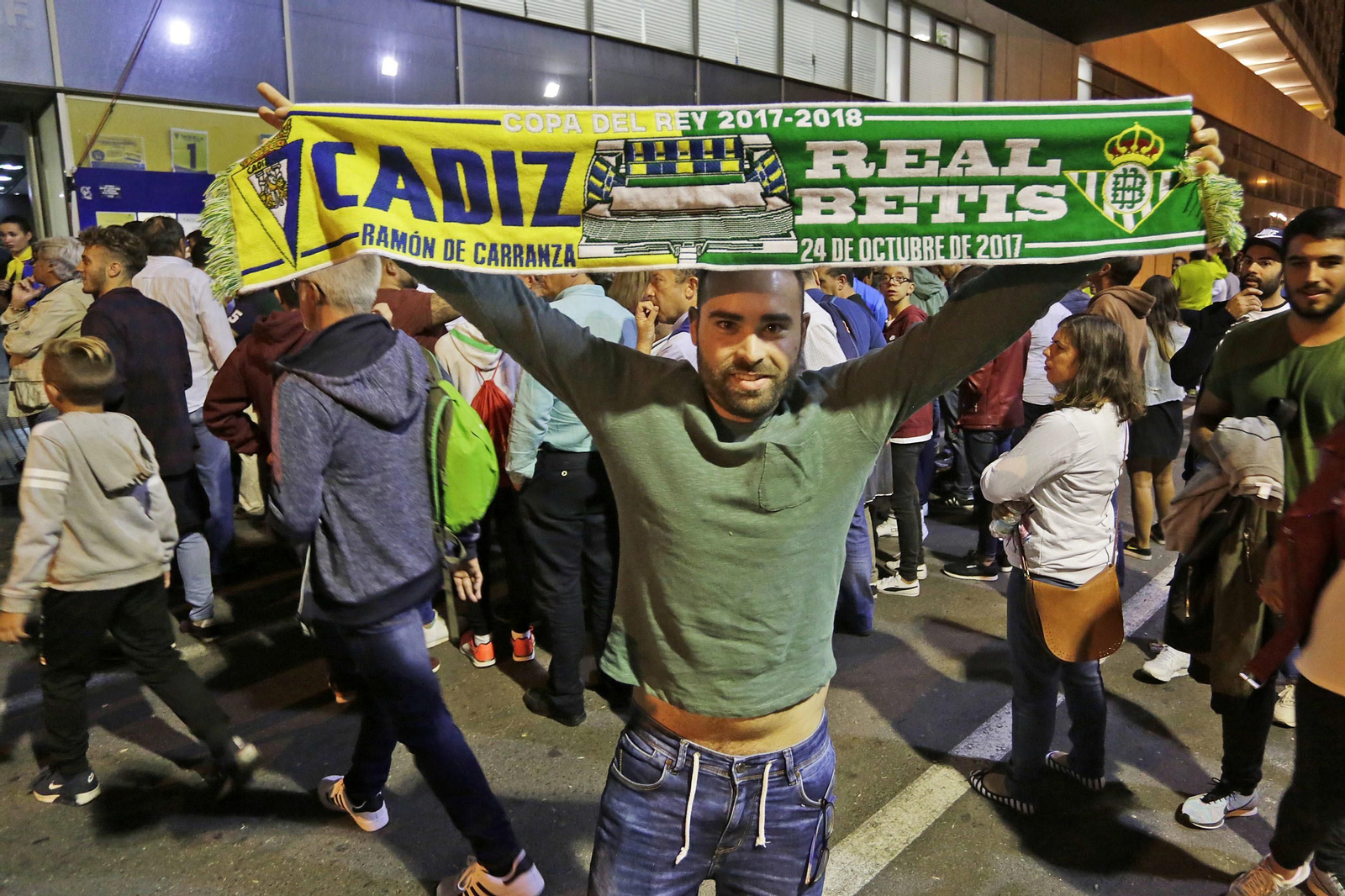 Un aficionado levanta una bufanda con los colores del Cádiz y el Betis.