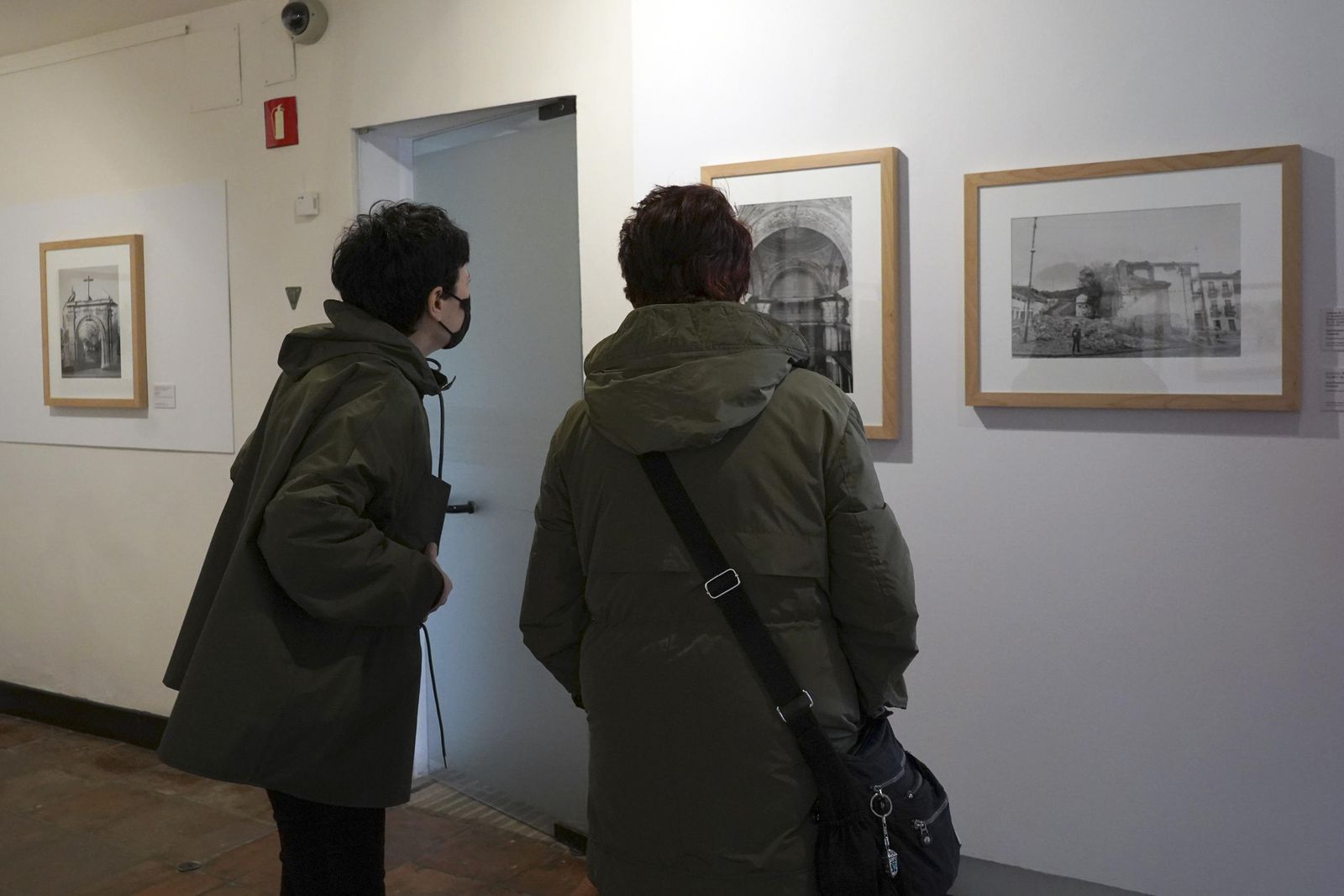 Dos personas observan varios de las imágenes expuestas.