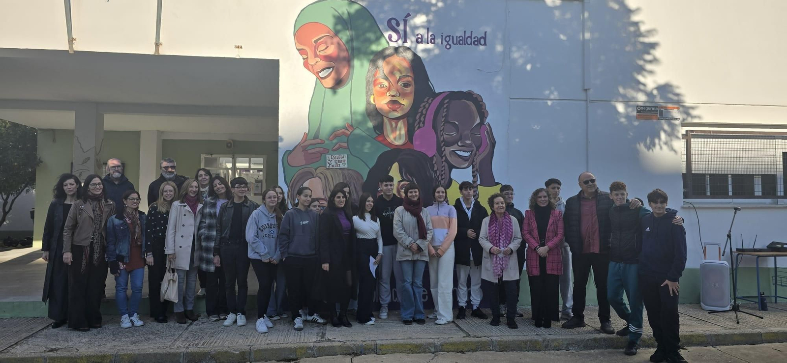 Foto de familia de los participantes en el acto frente al mural.