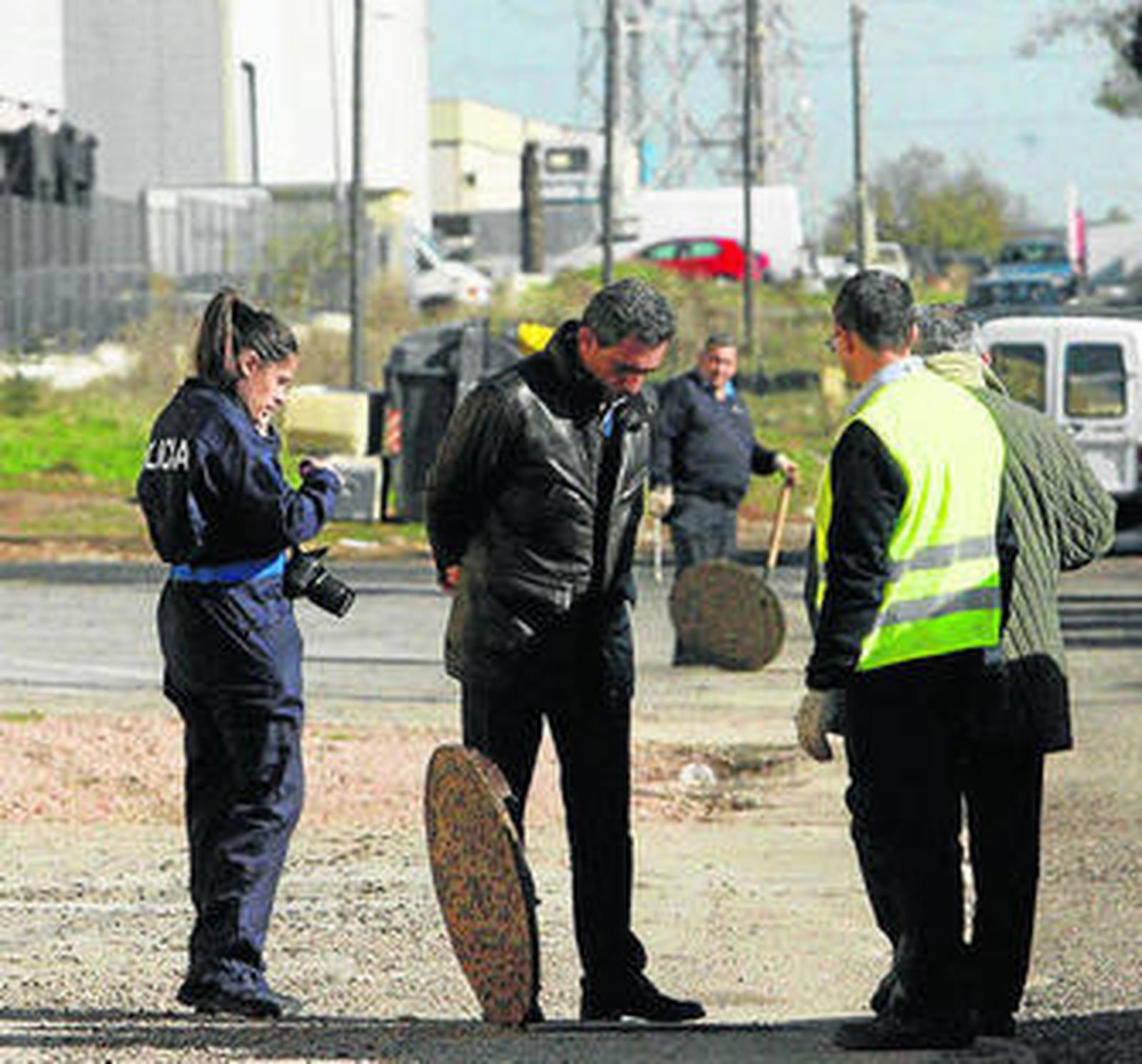 Agentes de la Policía y técnicos de Emacsa miran una arqueta.