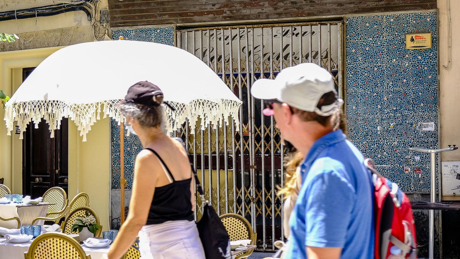 Unos turistas pasan por delante del único edificio y local vacío de toda la calle.