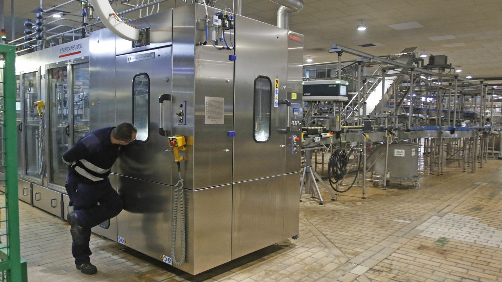 Un trabajador supervisa la producción de latas de cerveza.