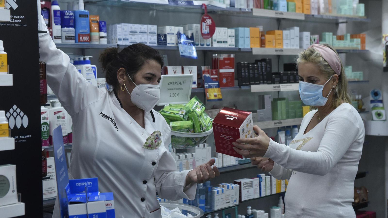 Una farmacéutica atiende a una paciente en la botica de Castilleja de la Cuesta.