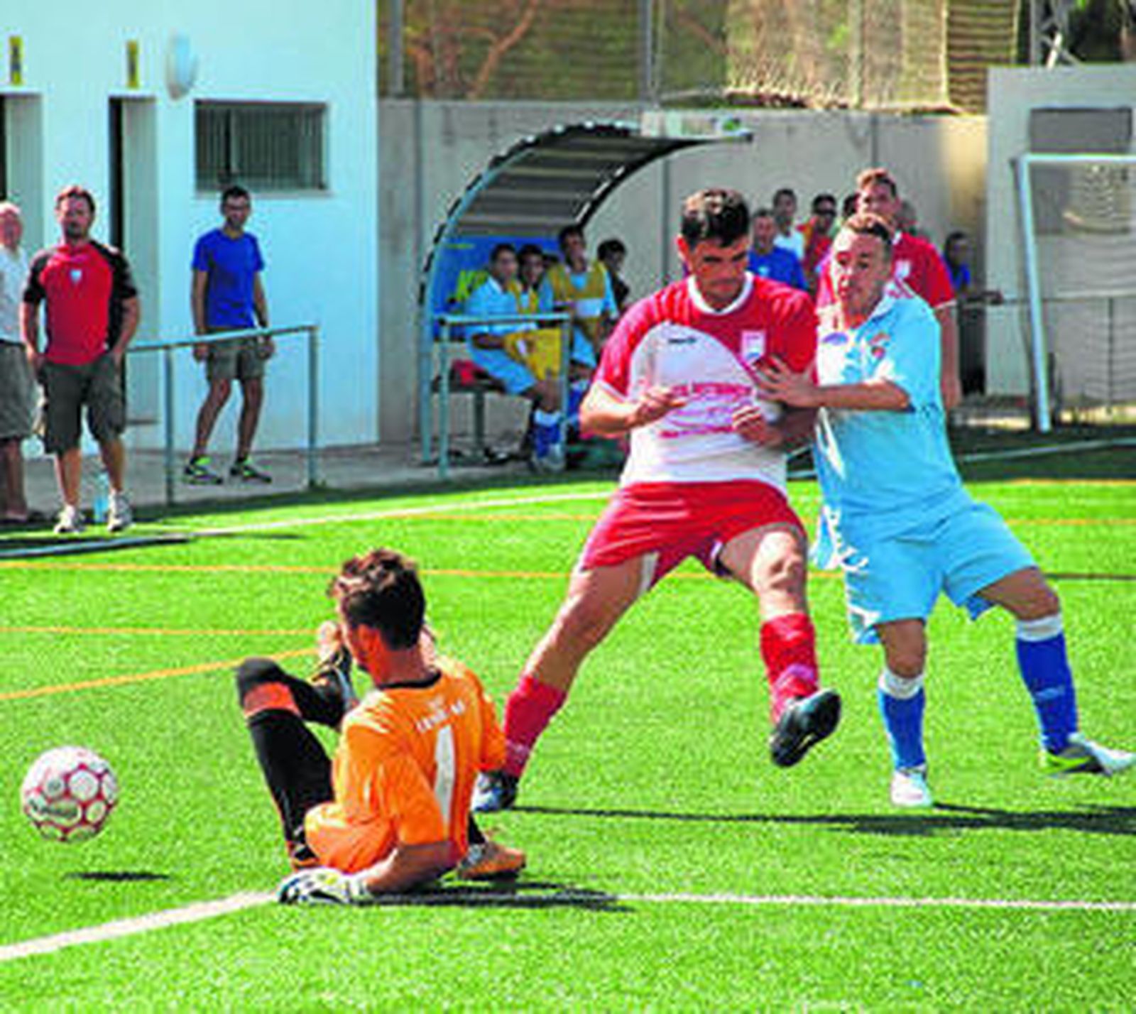 Carlos I, portero del Colorado, se lanza al suelo ante dos rivales.