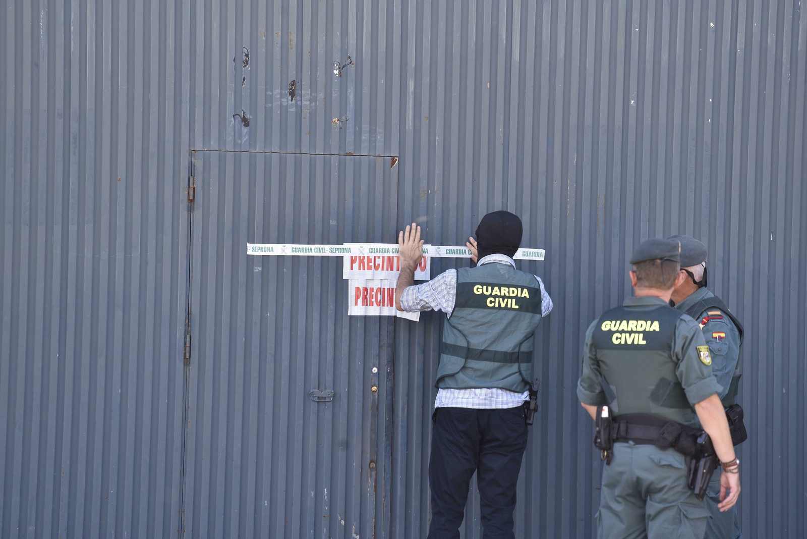 Varios agentes precintan las instalaciones de Magrudis, en el polígono industrial El Pino de Sevilla.