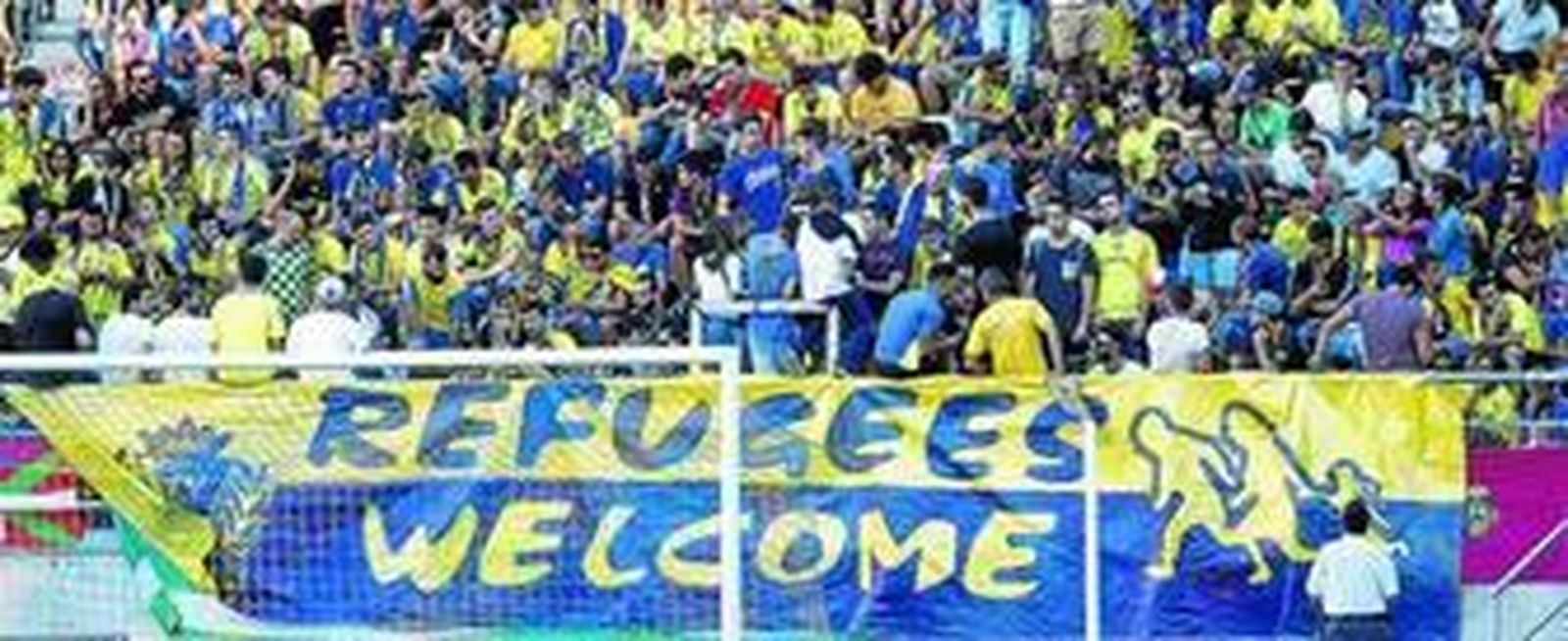 1. Una pancarta de carácter solidario da la bienvenida a los refugiados en inglés. 2. Un nutrido grupo de aficionados del Algeciras animaron a su equipo desde una esquina de Preferencia. 3. Augusto César Lendoiro, en el palco con el presidente del Cádiz. 4. El alcalde de Cádiz (d) no se perdió el partido en compañía de Teresa Rodríguez (i).