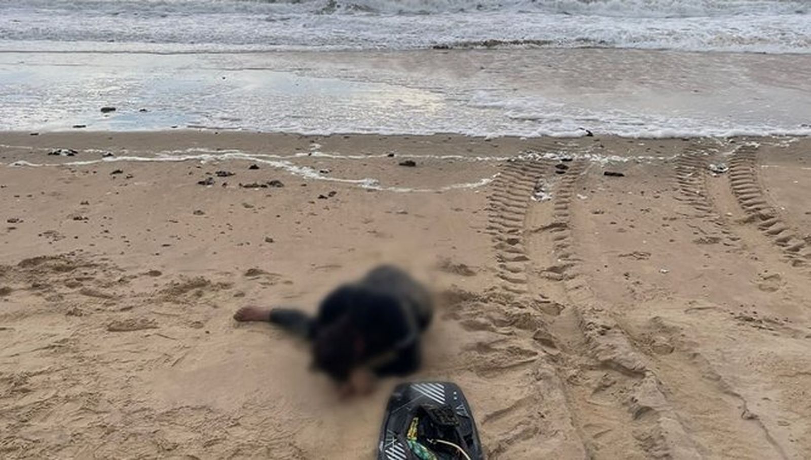 El deportista, completamente exhausto, en la orilla de la playa.
