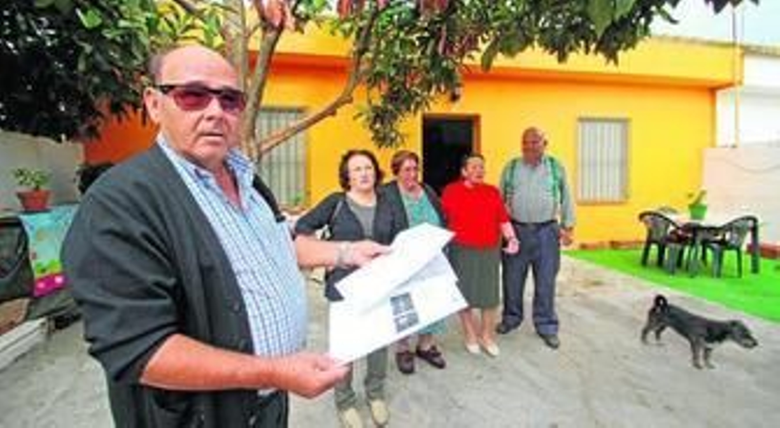 Juan Yerga muestra papeles ante su casa, acompañado por su mujer, María, Josefa y Manuel, otras dos de las familias afectadas.