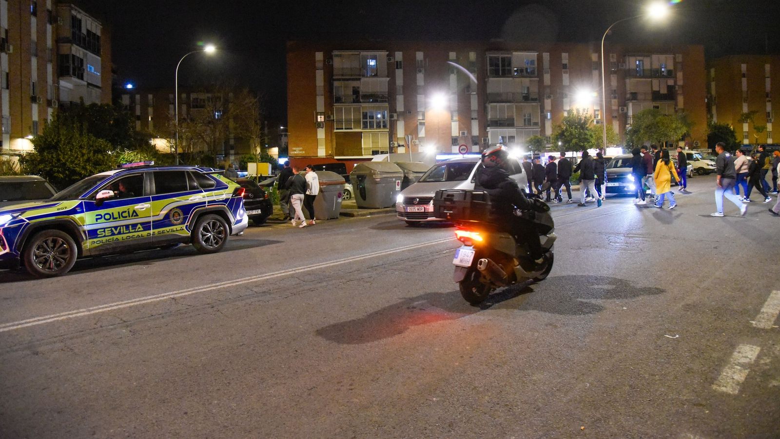Un coche de la Policía Local pasa ante el grupo vecinal por la avenida de San Lázaro.