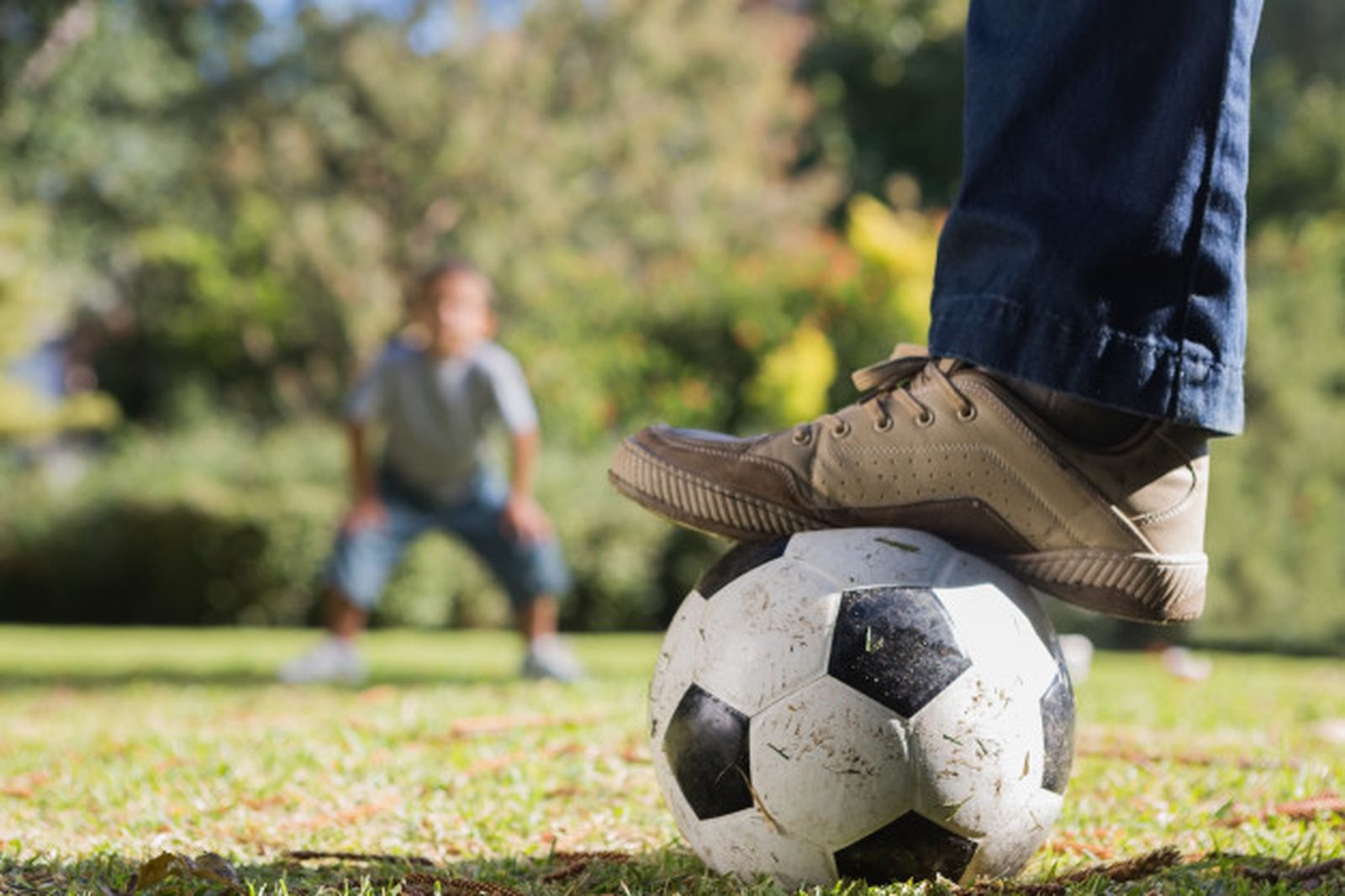 Un hombre y su hijo, juntos con un balón de fútbol por medio.