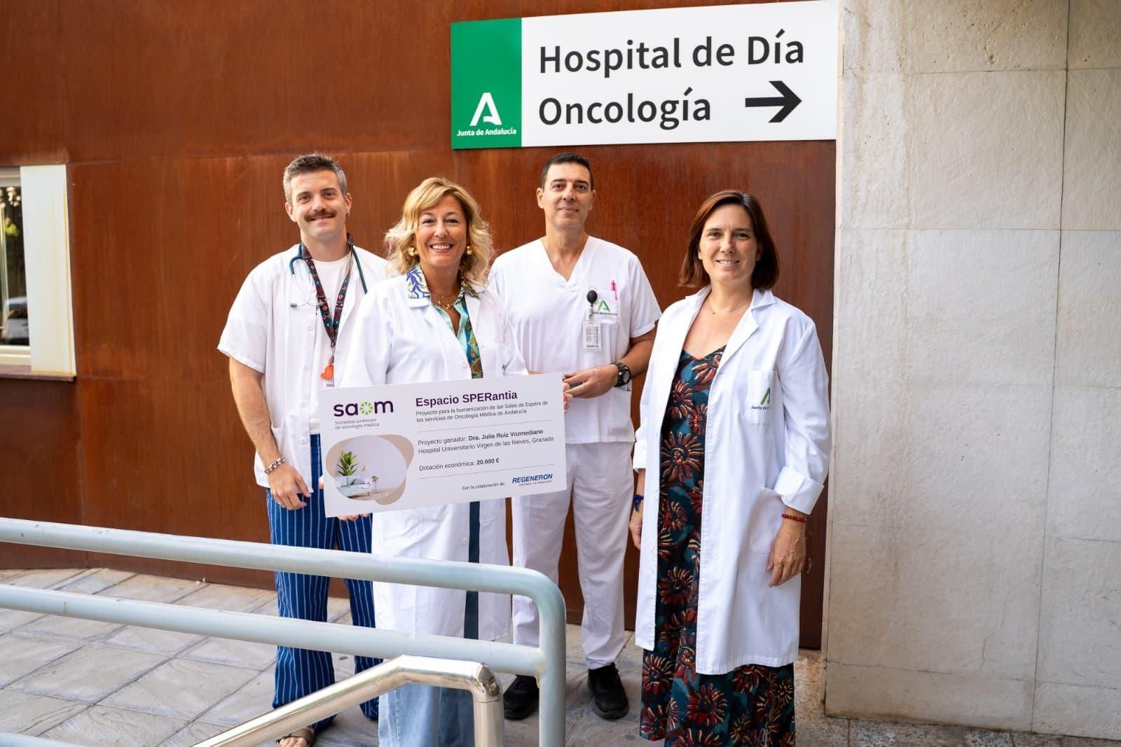 La oncóloga Encarnación González muestra el diploma de la beca junto a parte del equipo