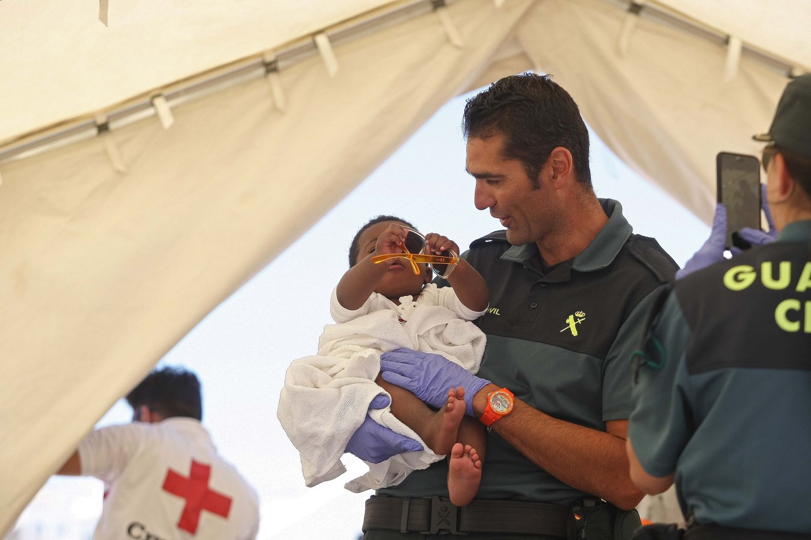 Un guardia civil juega con un menor recién llegado en patera a Tarifa.