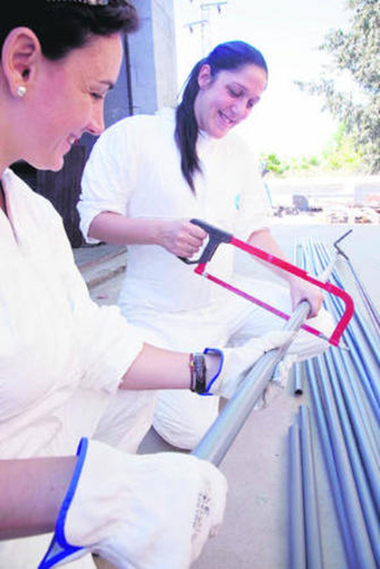Dos alumnas cortan con la sierra una tubería en los talleres de Emasesa.