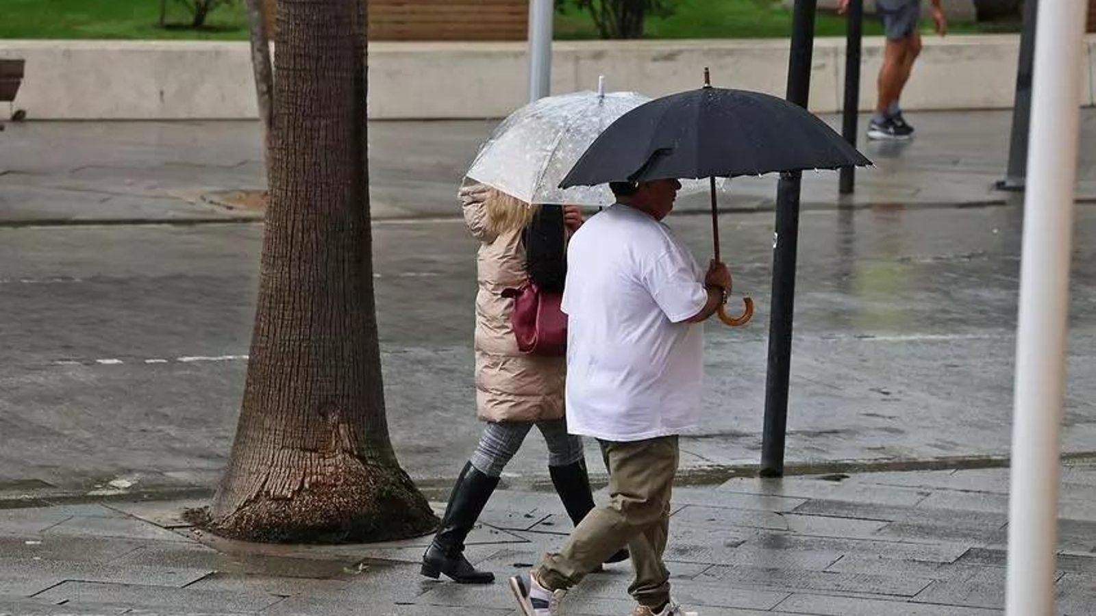 Dos personas con paraguas por las calles de Hueva.