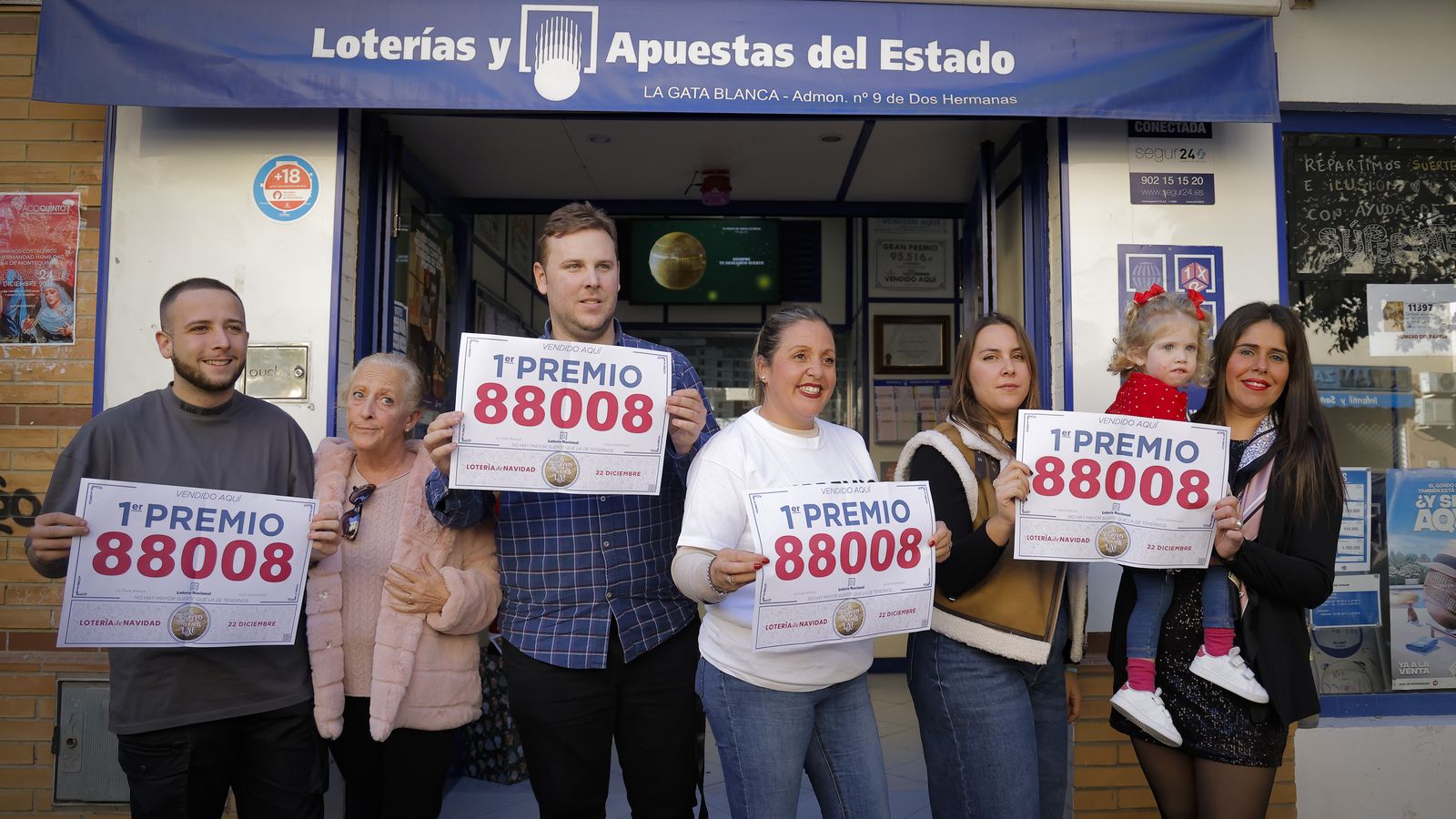 Los responsables y trabajadores de La Gata Blanca muestran el número del Gordo que han vendido.