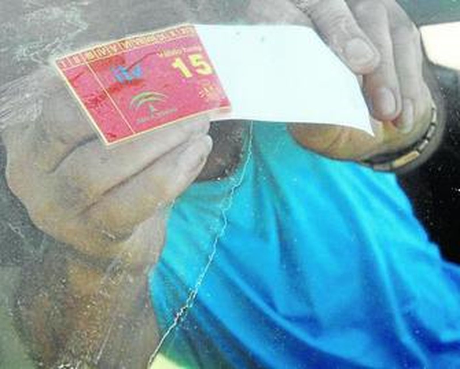 Un hombre coloca la pegatina de la ITV en su vehículo.