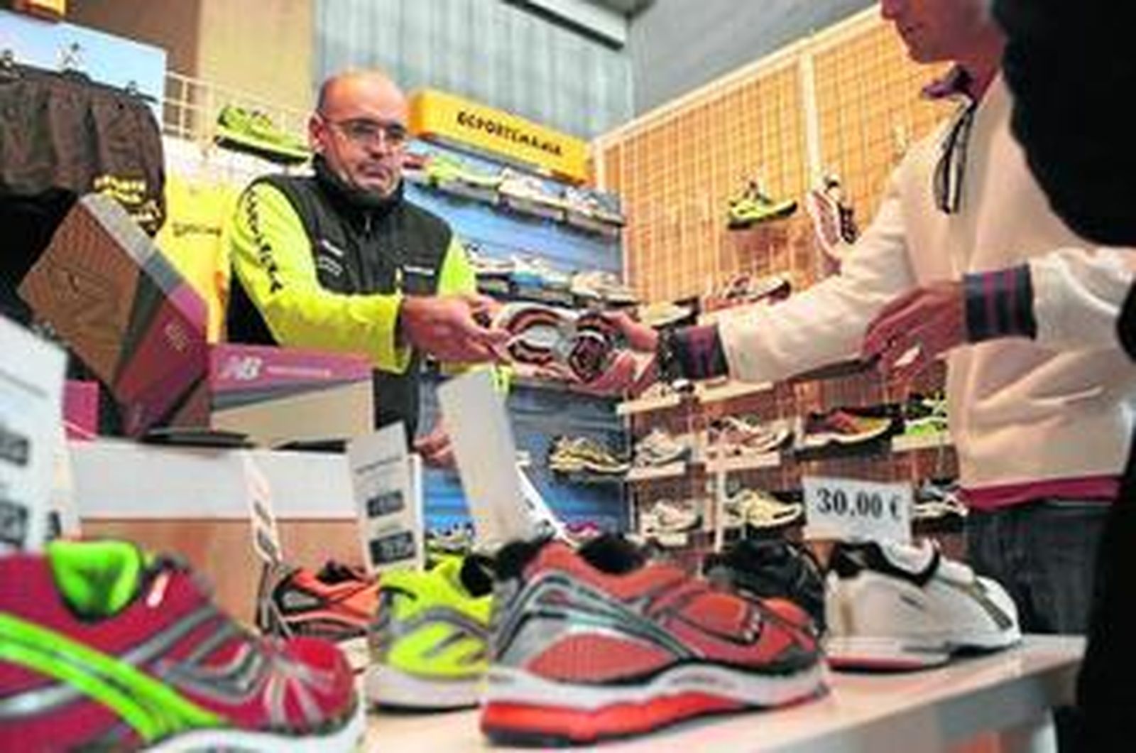 Varias personas ojean los productos que ofrece el 'stand' Deportemanía.