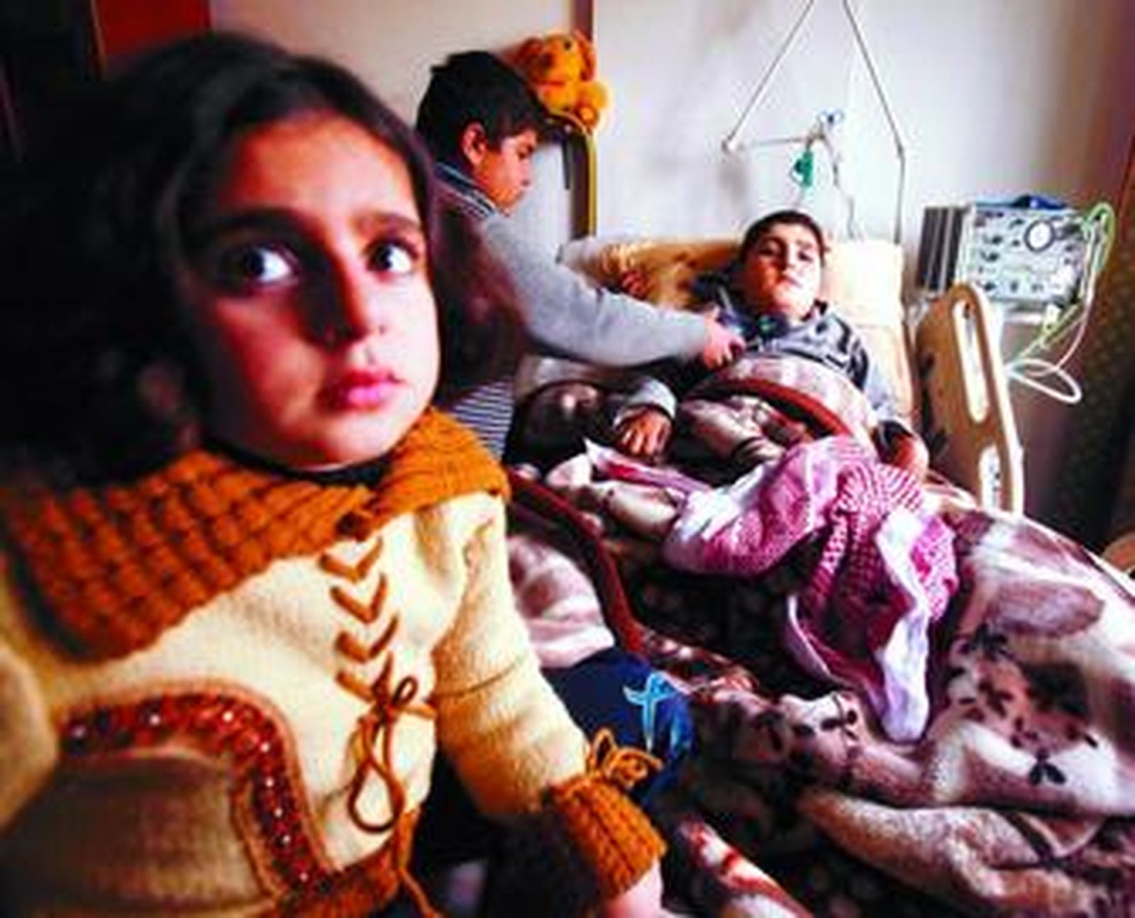 Un niño palestino cuida a su hermano enfermo en su casa en la Franja.