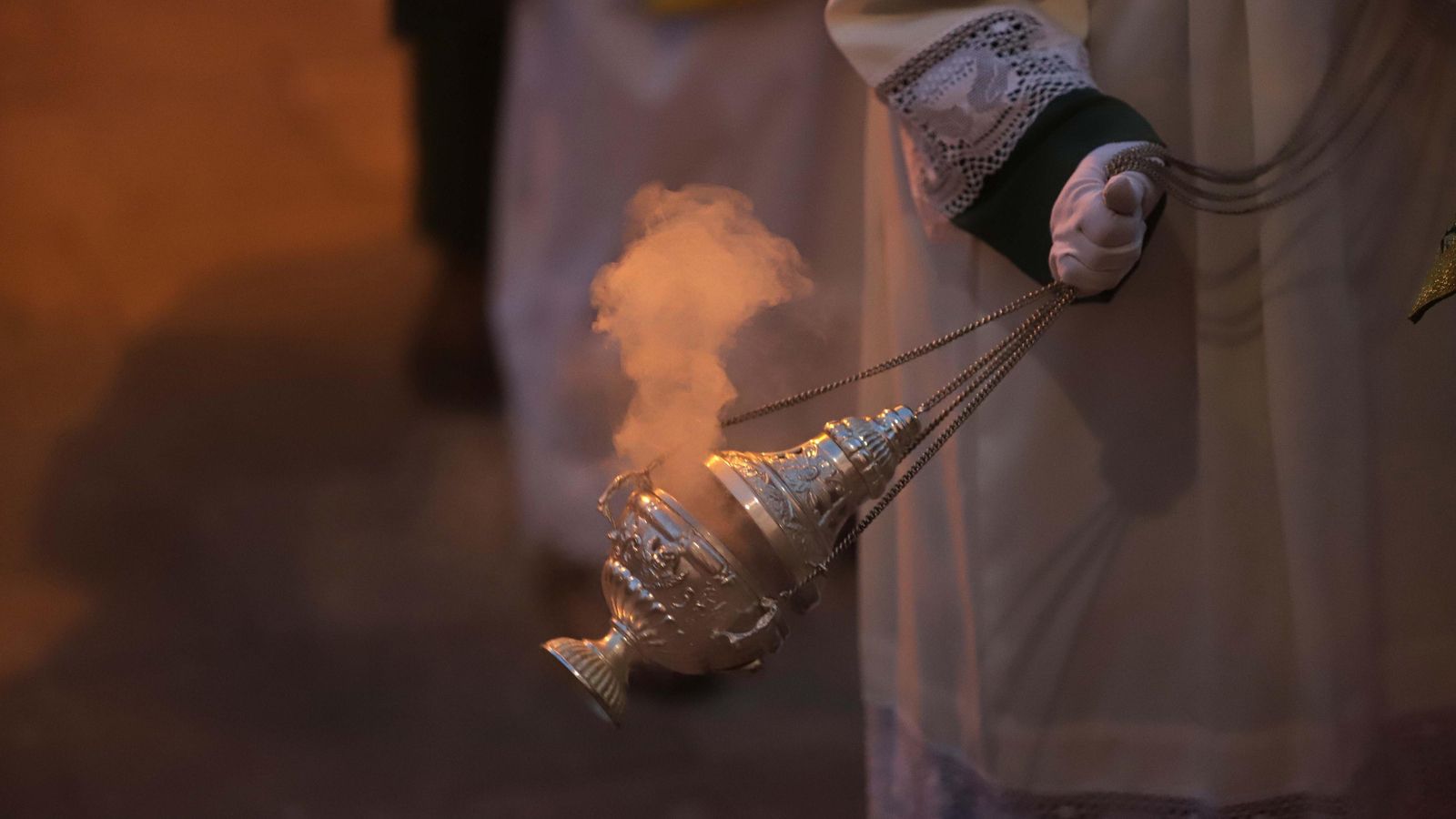 Un acólito reparte aroma de incienso.